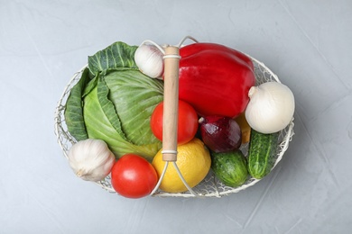 Photo of Basket with ripe fruits and vegetables on light table, top view