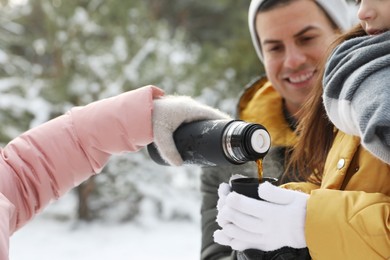 Photo of Happy family with thermos outdoors on winter day, closeup. Christmas vacation