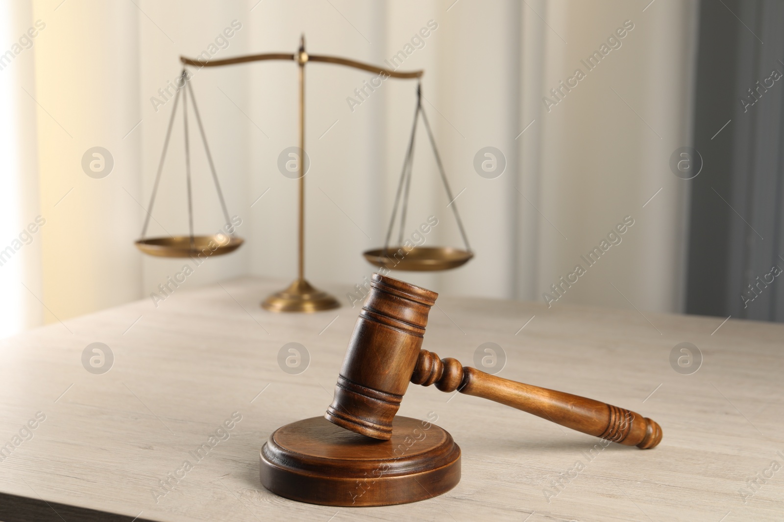 Photo of Law concept. Judge's mallet and scales of justice on light wooden table indoors