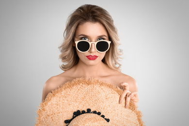 Photo of Young woman wearing stylish sunglasses on light grey background