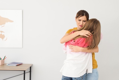 Happy mother hugging her teenager daughter at home