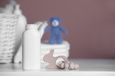 Bottle of baby cosmetic product and wooden toy on white table. Space for text