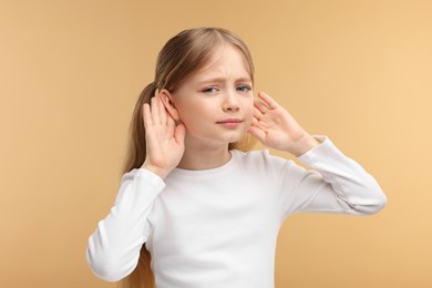 Photo of Little girl with hearing problem on pale brown background