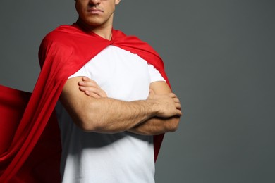 Man wearing superhero cape on grey background, closeup. Space for text