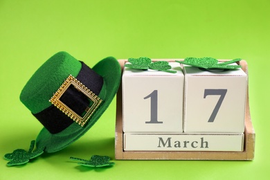 Photo of Leprechaun's hat, block calendar and St. Patrick's day decor on green background