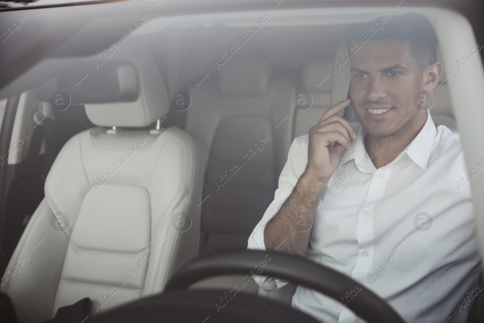 Photo of Handsome man talking on phone in his modern car