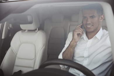 Handsome man talking on phone in his modern car