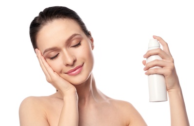 Photo of Young woman applying thermal water on face against white background. Cosmetic product