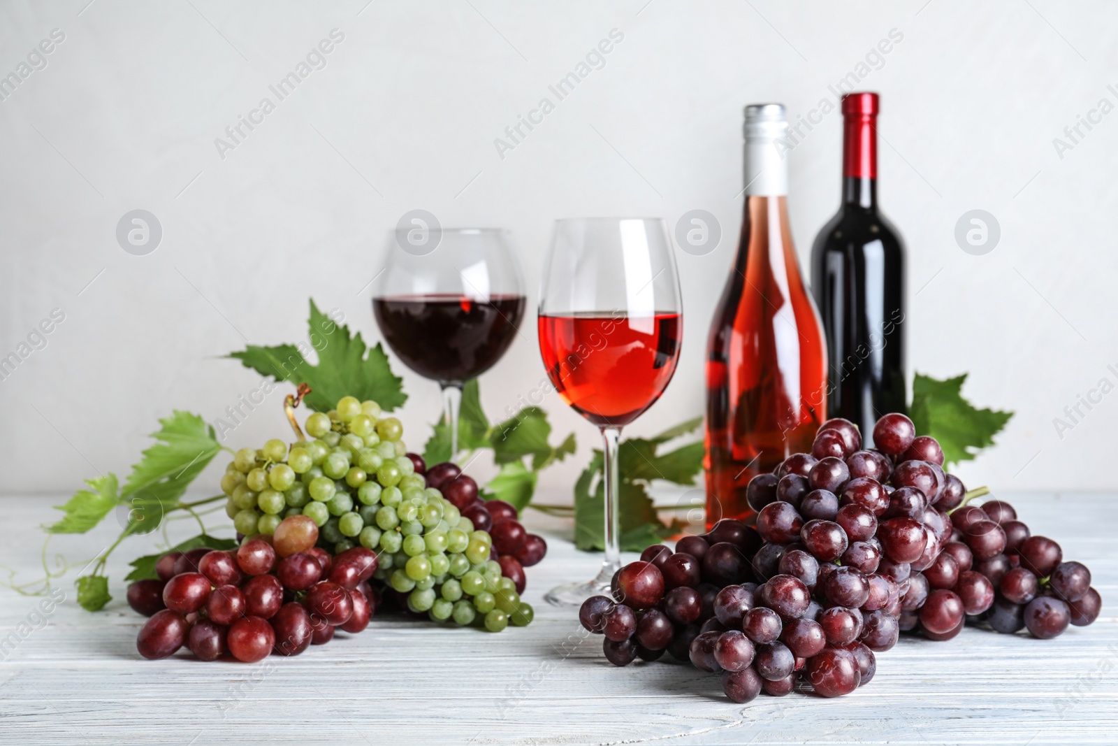 Photo of Fresh ripe juicy grapes and wine on white wooden table