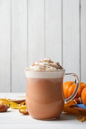 Photo of Delicious pumpkin latte with whipped cream on white table