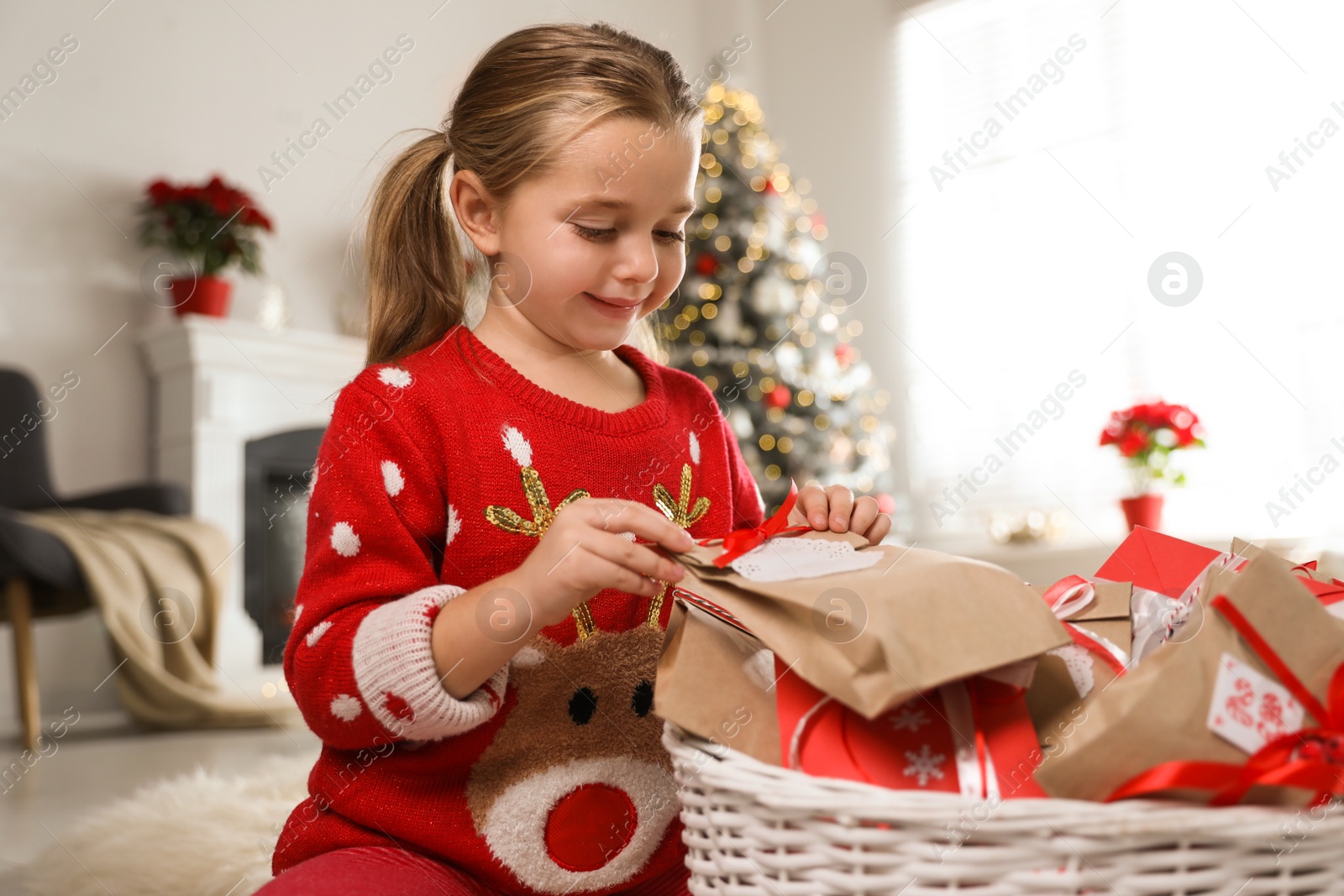 Photo of Cute little girl taking gift from Christmas advent calendar at home