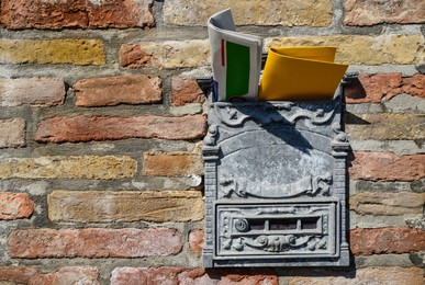 Photo of Vintage post box with newspaper and letter on old brick wall. Space for text