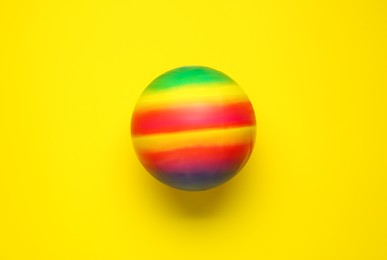 Photo of Bright rubber kids' ball on yellow background, top view