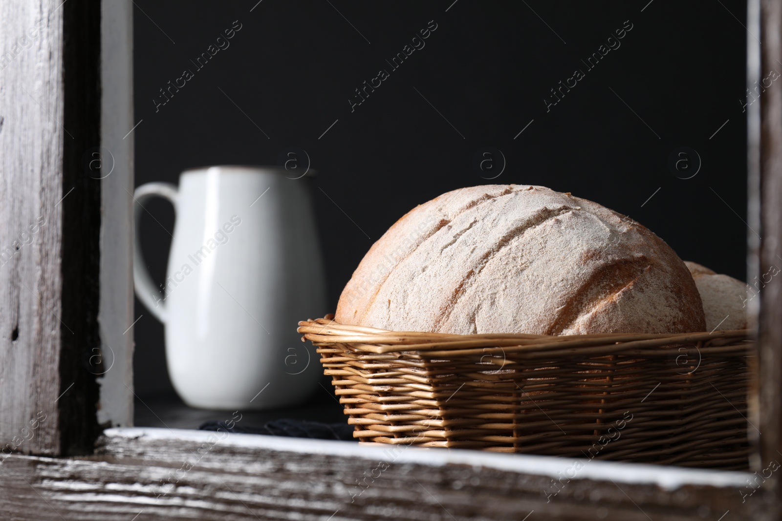 Photo of Fresh homemade bread in wicker basket, view through window