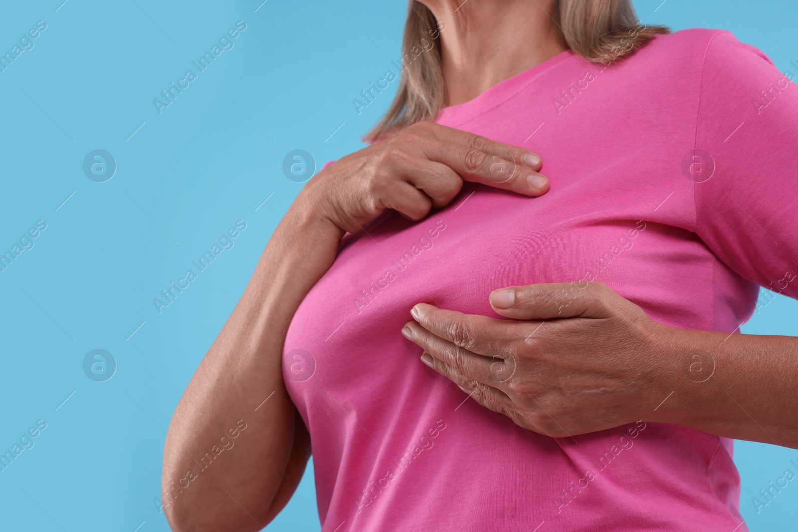 Photo of Woman doing breast self-examination on light blue background, closeup. Space for text