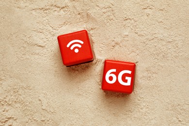 Photo of 6G technology, Internet concept. Red cubes with WiFi symbol on sand, flat lay