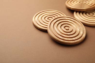 Stylish wooden cup coasters on brown background, space for text