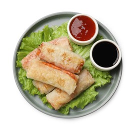 Photo of Delicious fried spring rolls and sauces isolated on white, top view