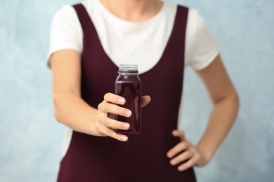 Woman with bottle of beet smoothie on light background, closeup