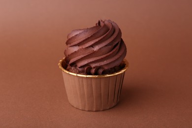 Delicious chocolate cupcake on brown background, closeup