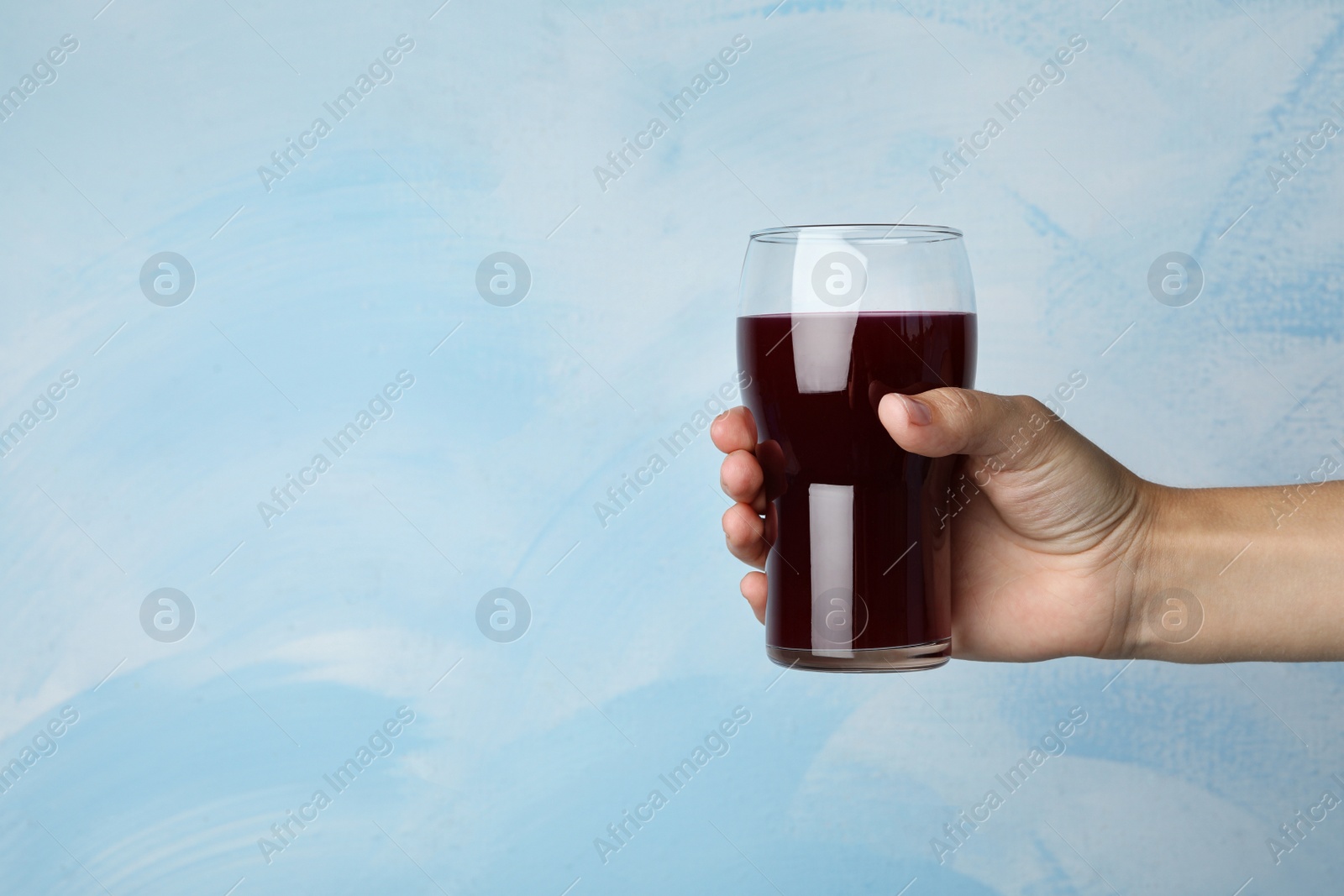 Image of Woman with glass of juice on light blue, closeup. Space for text 