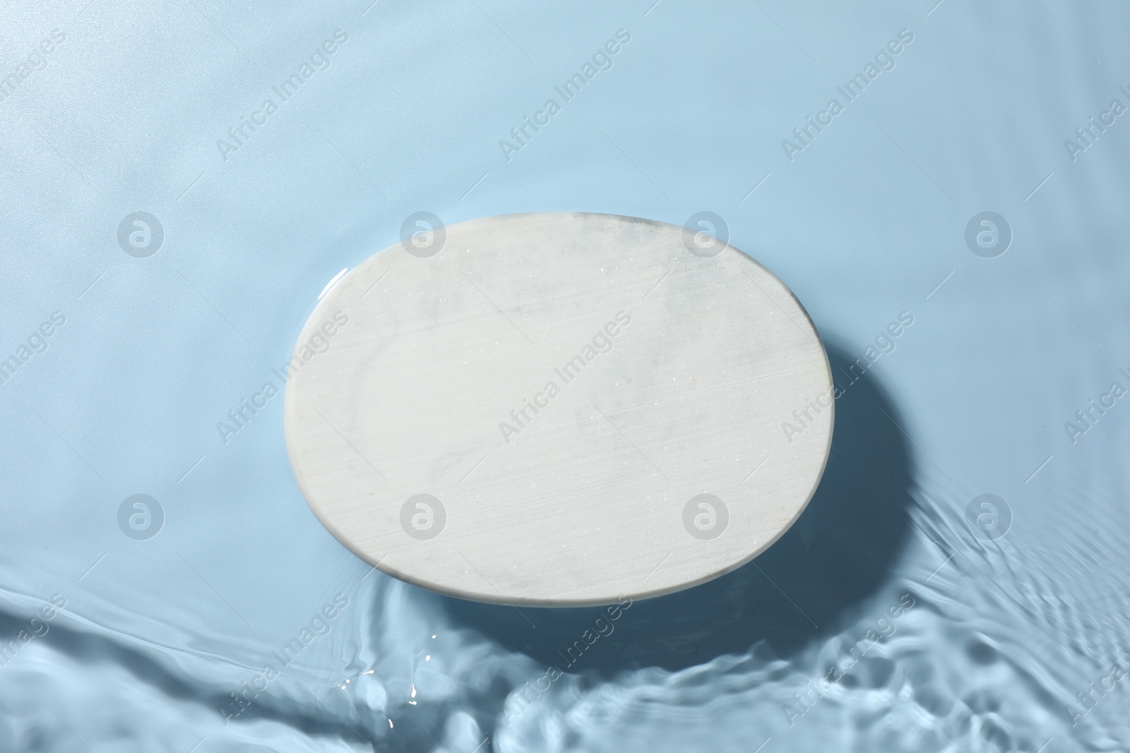 Photo of Presentation for product. White podium in water on light blue background, top view