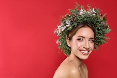 Photo of Beautiful young woman wearing Christmas wreath on red background. Space for text