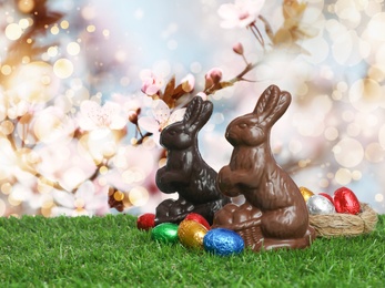 Chocolate bunnies and eggs on green grass outdoors. Easter celebration