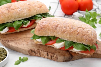 Photo of Delicious Caprese sandwiches with mozzarella, tomatoes and basil on white wooden table, closeup