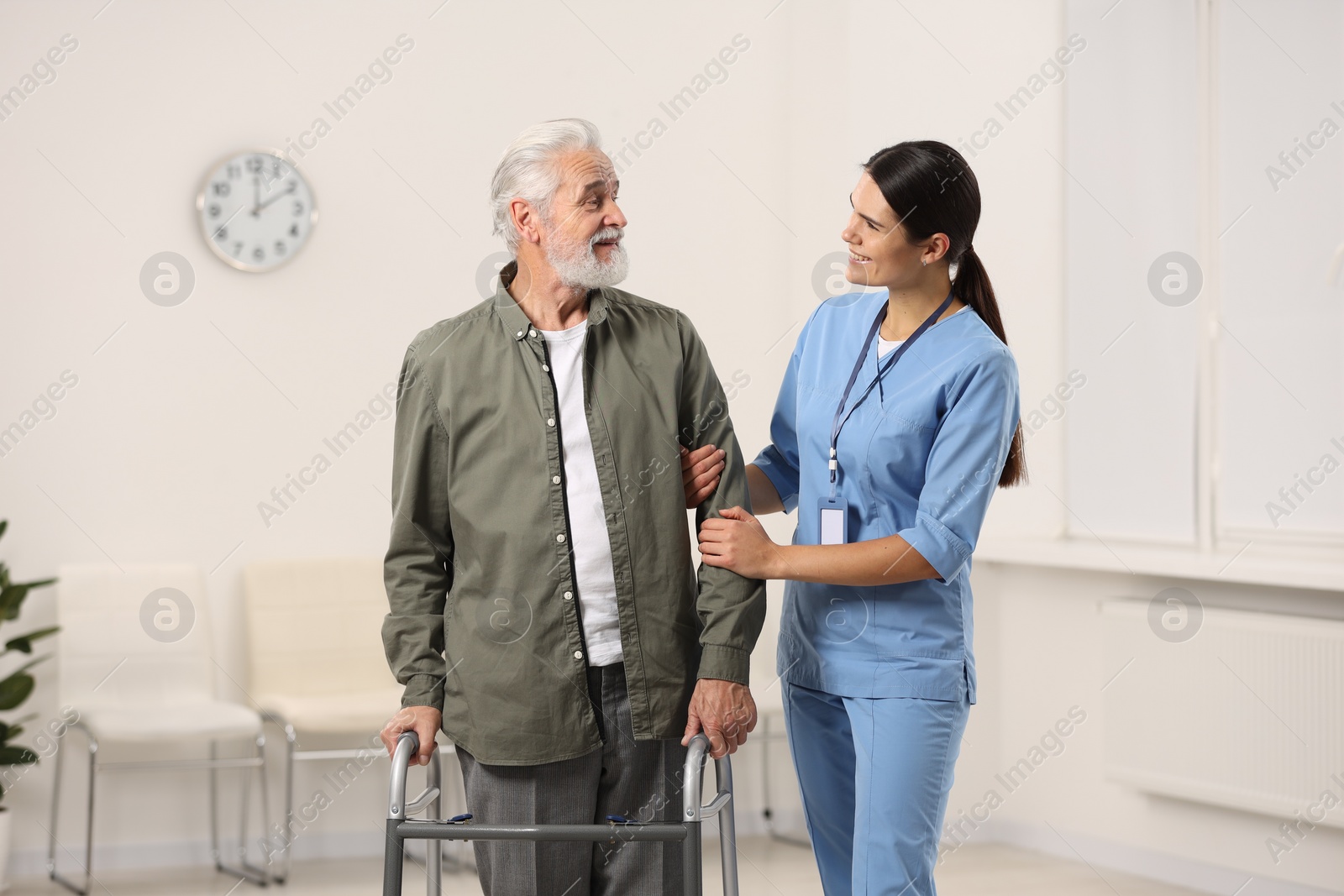 Photo of Smiling nurse supporting elderly patient in hospital