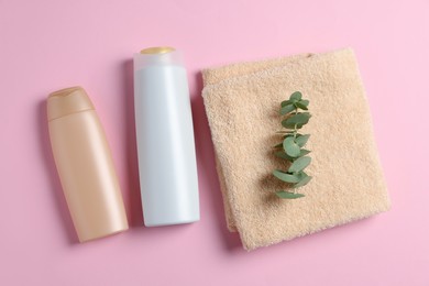 Photo of Soft folded towel with eucalyptus branch and cosmetic products on pink background, flat lay