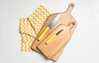 Photo of Wooden boards and knives on white background, top view. Cooking utensils