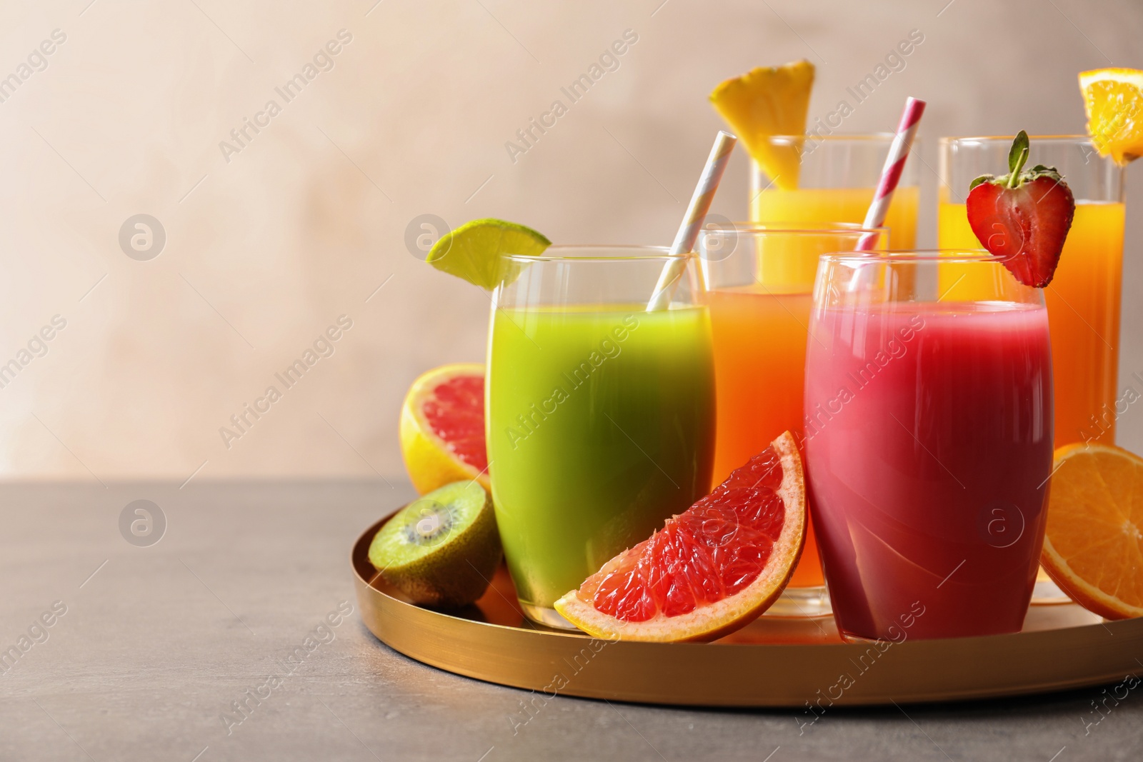 Photo of Tray with glasses of different juices and fresh fruits on table. Space for text