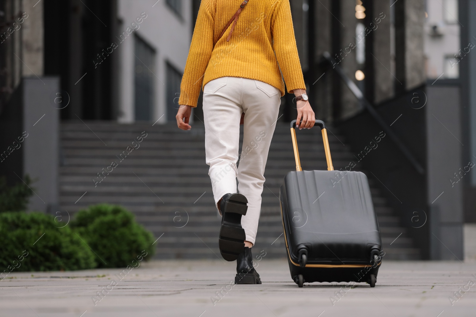 Photo of Being late. Woman with suitcase running towards building outdoors, closeup