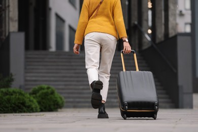 Photo of Being late. Woman with suitcase running towards building outdoors, closeup