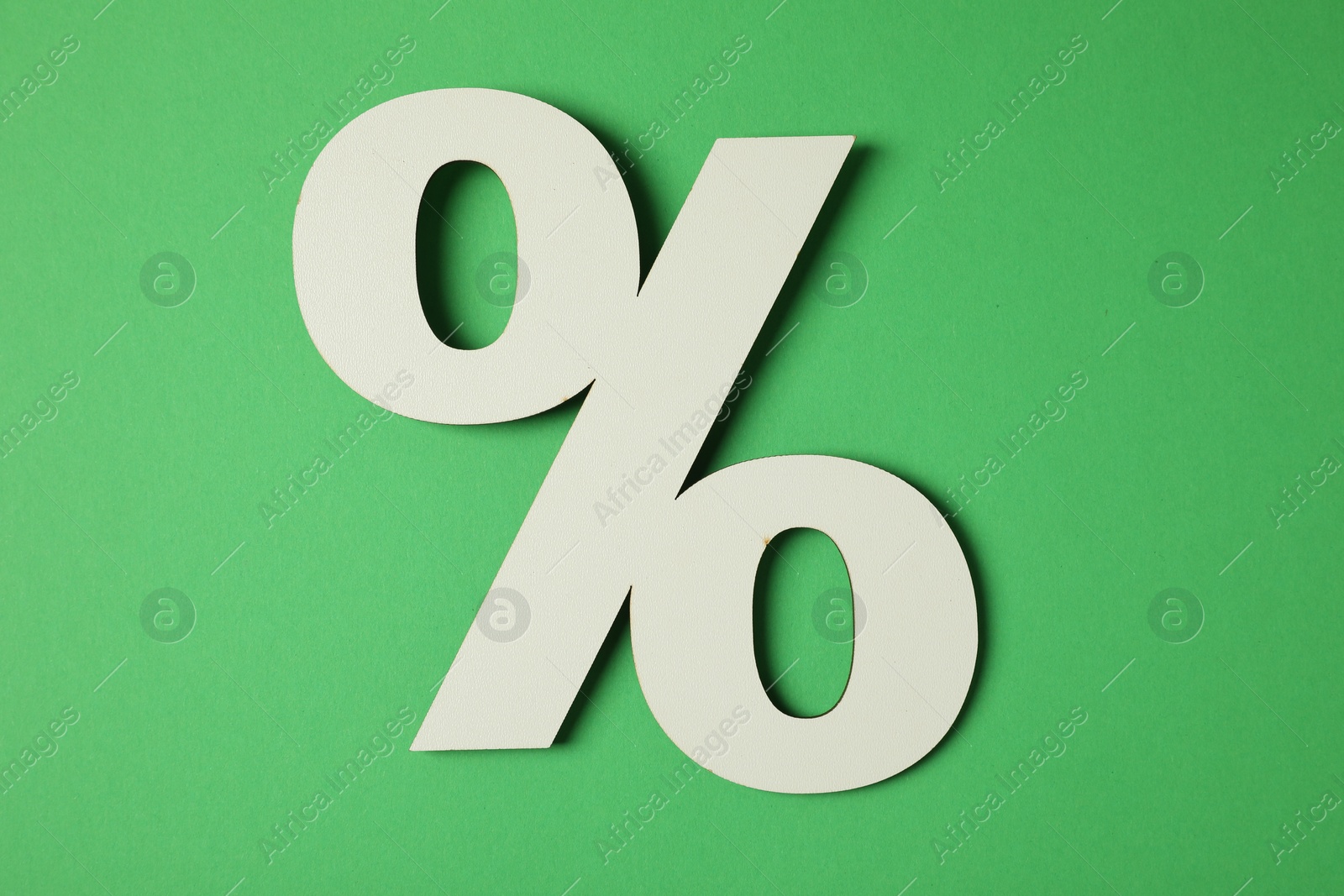 Photo of Wooden percent sign on green background, top view