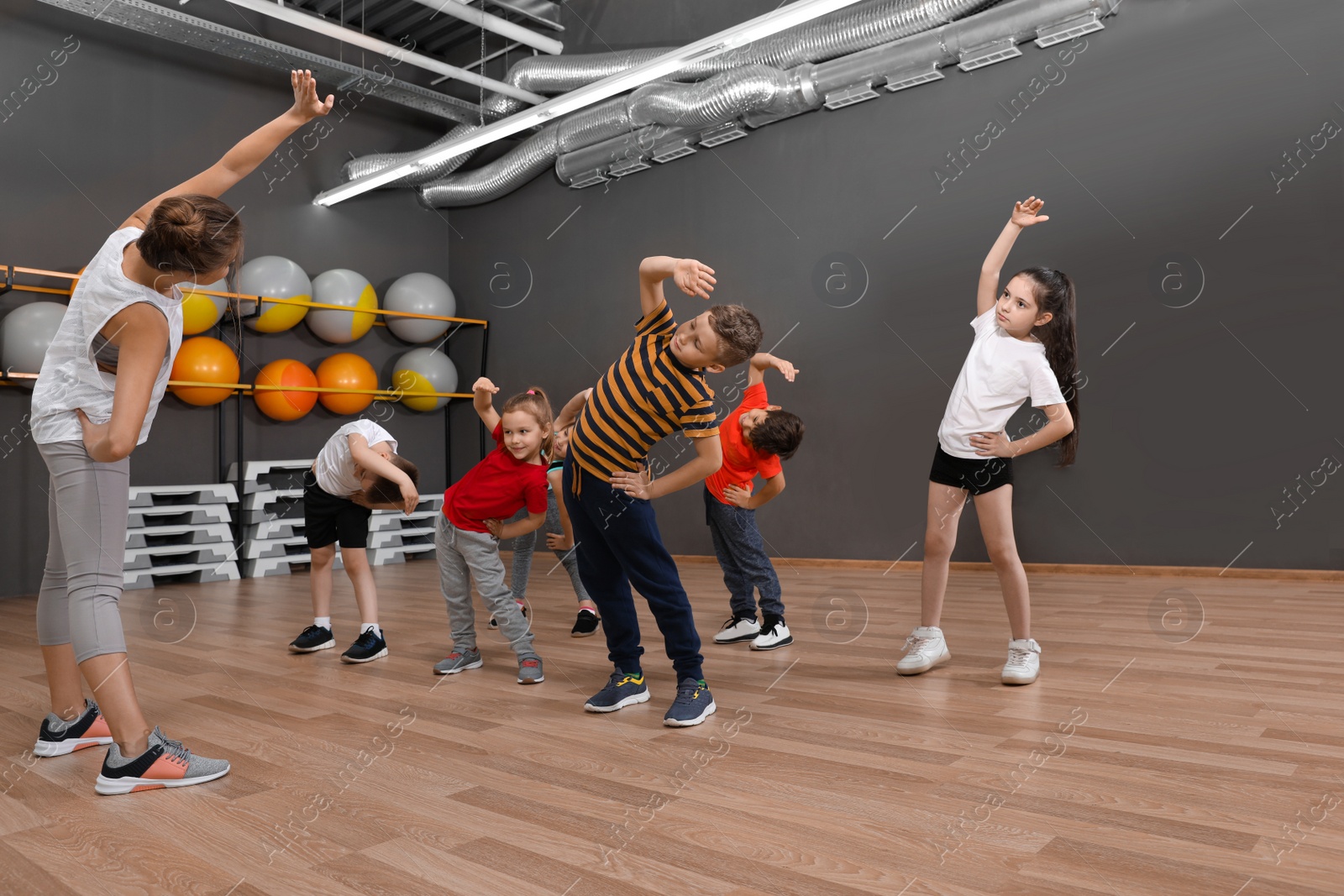 Photo of Cute little children and trainer doing physical exercise in school gym. Healthy lifestyle