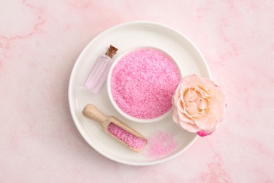 Bowl and scoop with sea salt, beautiful rose on pink marble table, top view