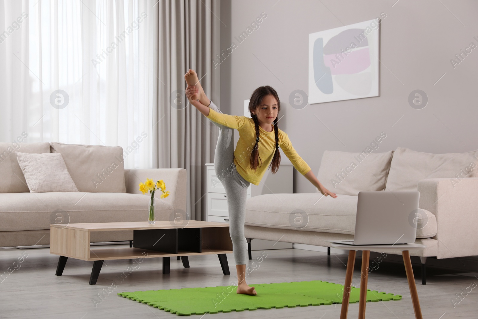 Photo of Cute little girl taking online dance class at home