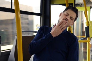 Sleepy tired man yawning in public transport