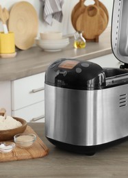 Photo of Breadmaker and products on wooden table in kitchen