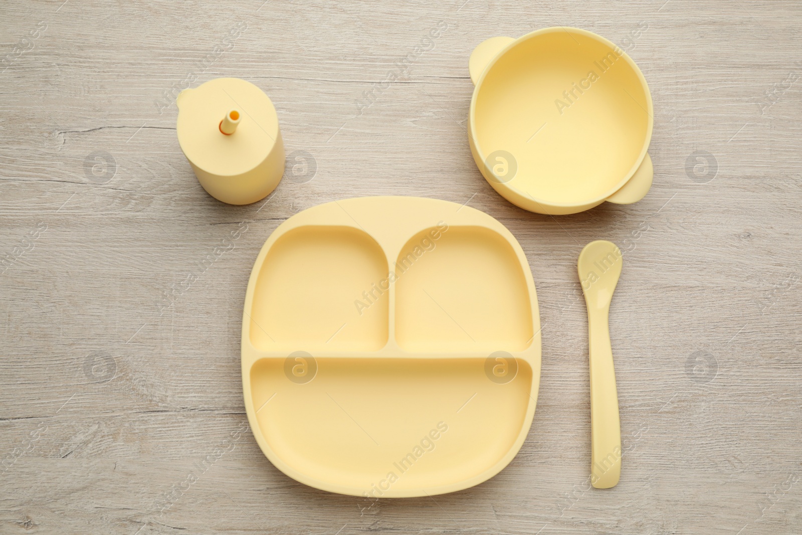 Photo of Set of plastic dishware on wooden background, flat lay. Serving baby food