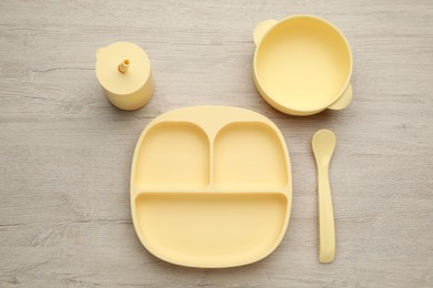 Set of plastic dishware on wooden background, flat lay. Serving baby food