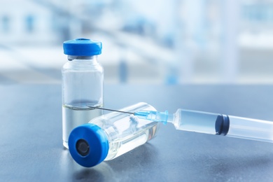 Photo of Vials and syringe with medicine on blurred background. Vaccination concept