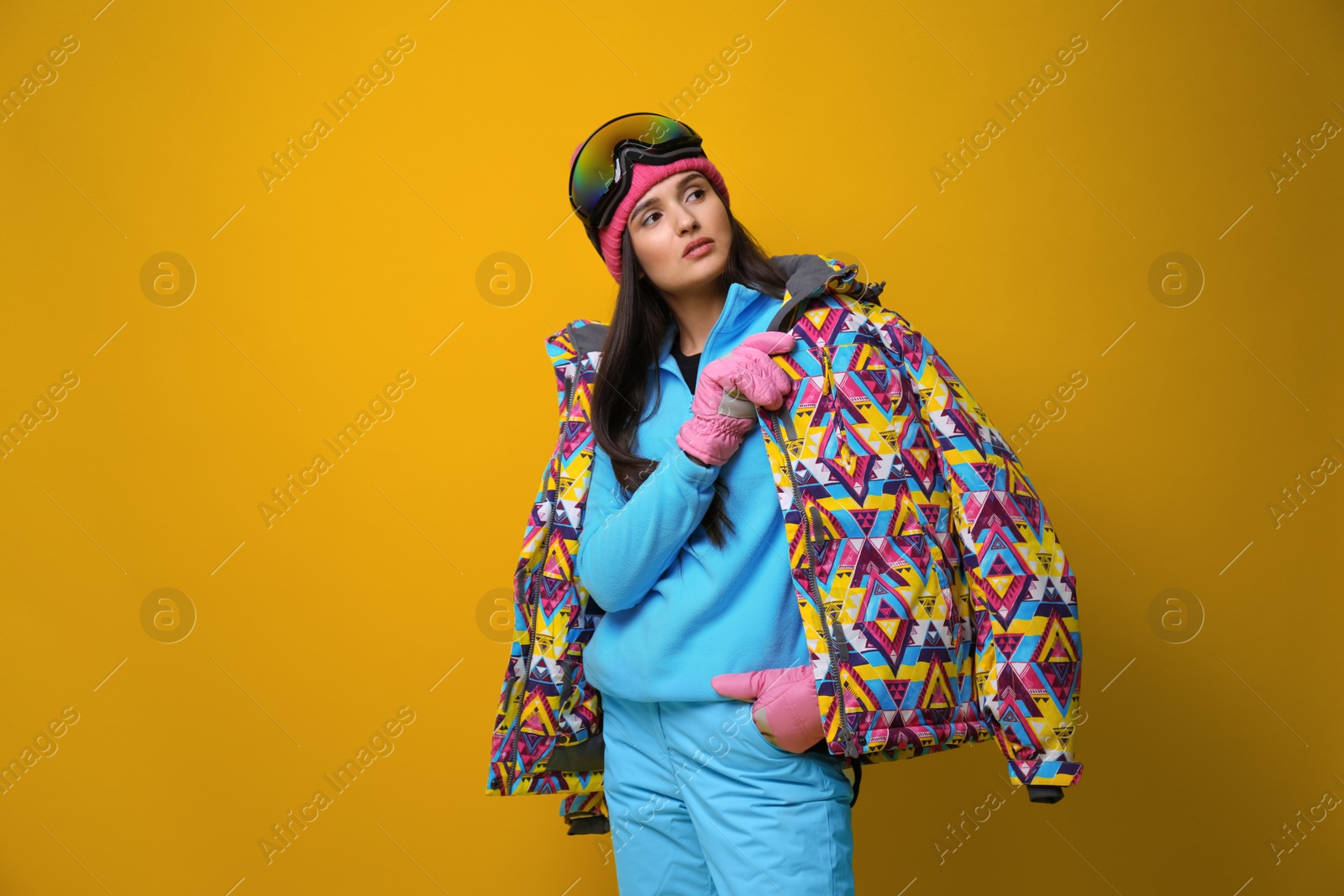 Photo of Woman wearing stylish winter sport clothes on yellow background