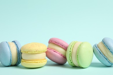 Delicious colorful macarons on light blue background, space for text