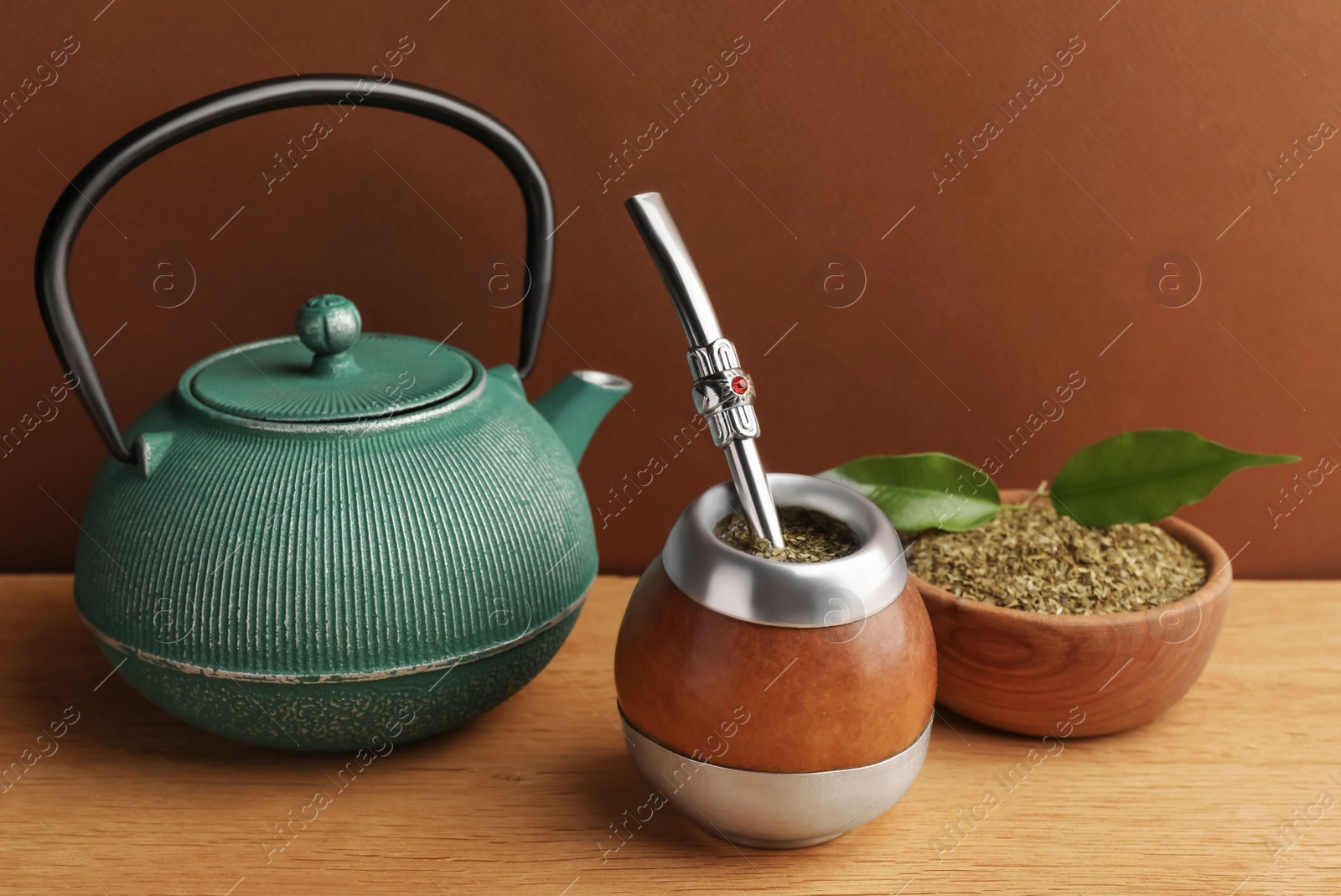 Photo of Calabash with mate tea, bombilla and teapot on wooden table