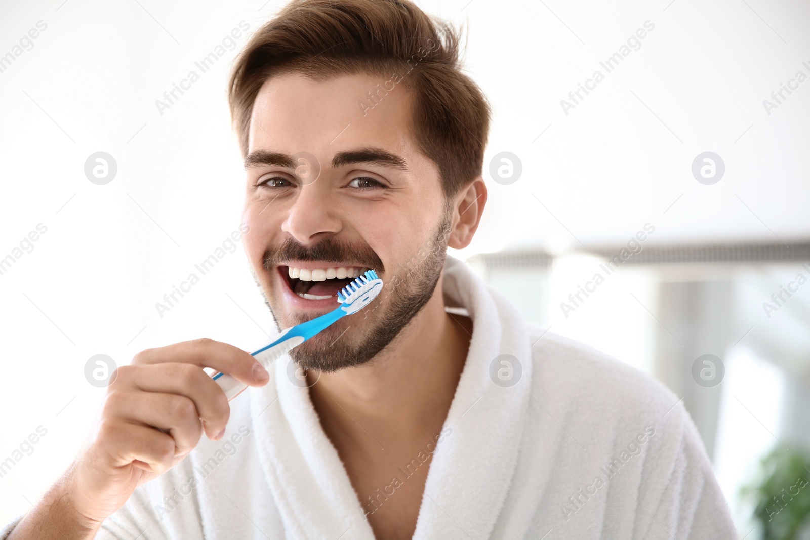 Photo of Portrait of young man with toothbrush in bathroom. Personal hygiene