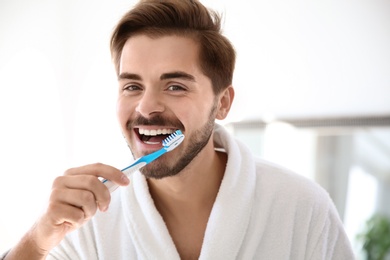 Portrait of young man with toothbrush in bathroom. Personal hygiene