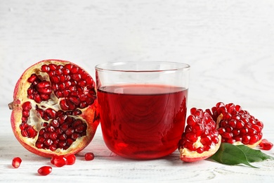 Photo of Glass of pomegranate juice and fresh fruits on wooden table